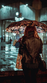 Rear view of woman with umbrella walking in rain