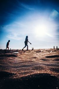 Silhouette men walking on beach against sky