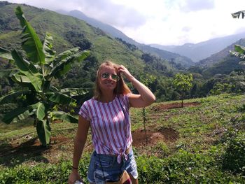 Young woman standing on field against sky