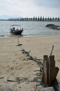 Boat moored on beach against sky