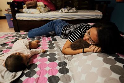 Top view of woman relaxing on bed at home with baby