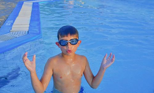 Cute little boy with swimming goggles in the swimming pool on summer day. summer and happy childhood