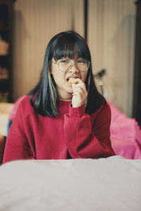 Close-up portrait of smiling girl holding snack against face