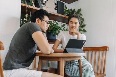 Young man using laptop while sitting on sofa at home