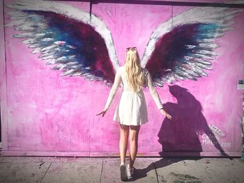 Rear view of woman standing against pink wall