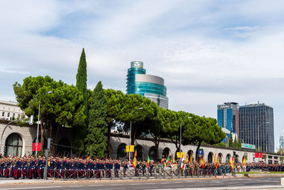 People by modern buildings against sky in city