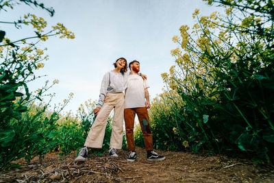 Friends standing by plants against sky