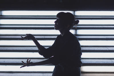 Silhoutte rear view of woman looking through window and posing vogue fashion