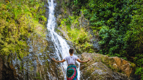 Rear view of woman standing in forest