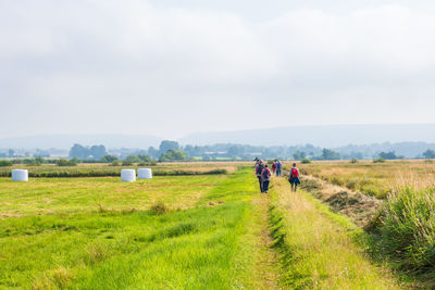 Rear view of man walking on field against sky