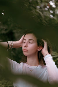 Beautiful young woman with eyes closed in forest