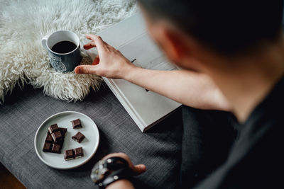 High angle view of man holding coffee cup on table
