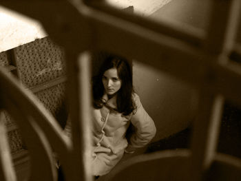 High angle portrait of woman sitting on window sill at home