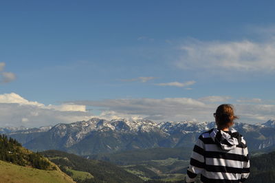 Rear view of woman standing on mountain against sky