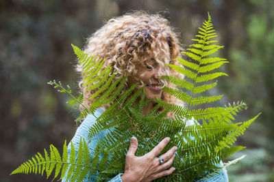 Smiling woman standing by plant outdoors