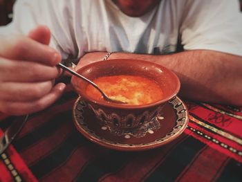 Midsection of man eating fresh tripe soup in bowl on table