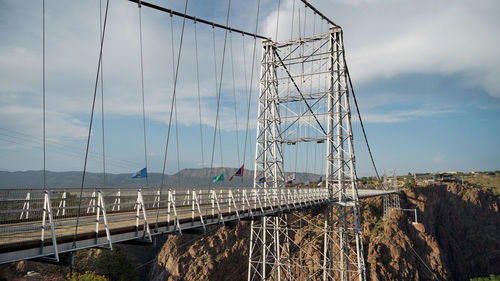 Suspension bridge over river against sky