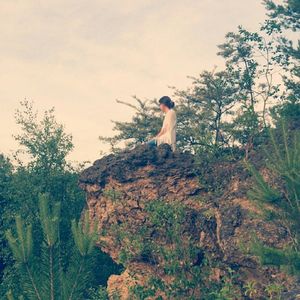 Woman standing by tree against sky