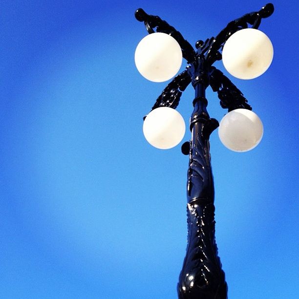 low angle view, blue, clear sky, lighting equipment, copy space, hanging, light bulb, electricity, sphere, electric light, illuminated, studio shot, balloon, street light, electric lamp, one person, decoration, ceiling, close-up, lantern