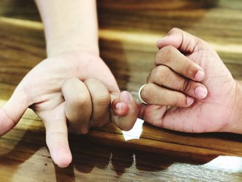 Cropped image of people holding hands on table