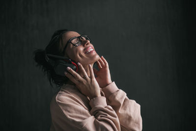 Portrait of smiling young woman against black background