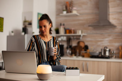 Young woman using digital tablet while sitting on table