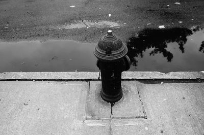 High angle view of fire hydrant on footpath by puddle