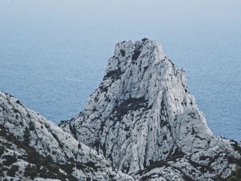 Scenic view of sea by mountain against clear sky