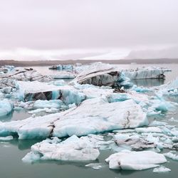 Scenic view of sea with floating ice caps against cloudy sky in iceland - jökulsárlón glacier lagoon