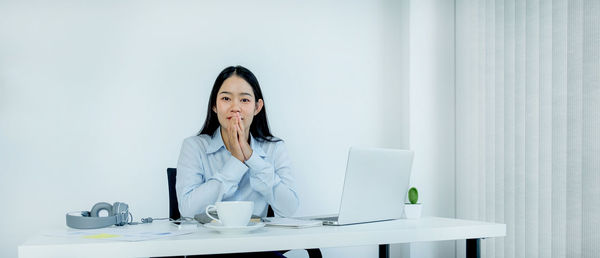 Portrait of woman using mobile phone while sitting on table