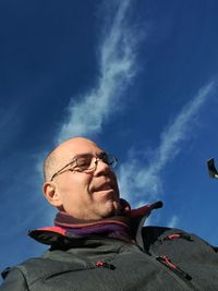 Low angle view of man standing against blue sky during sunny day