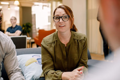 Confident businesswoman wearing eyeglasses while sitting in office