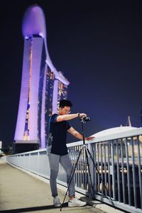 Full length of young man photographing on bridge at night