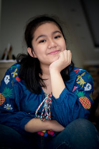 Portrait of smiling young woman sitting at home