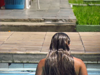Rear view of young woman relaxing at poolside