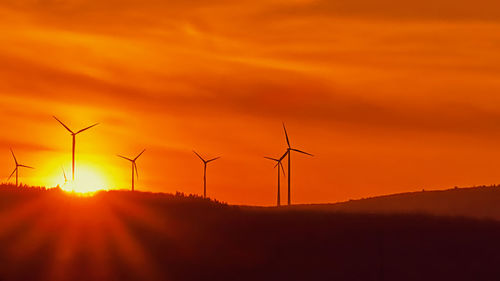 Silhouette wind turbine against sky during sunset