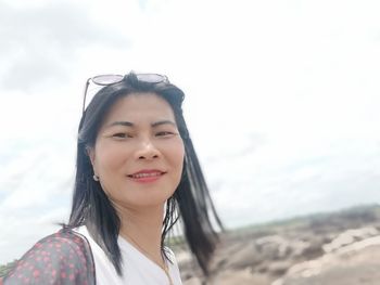 Portrait of smiling young woman on beach against sky