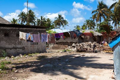 Clothes drying on clothesline by houses against sky