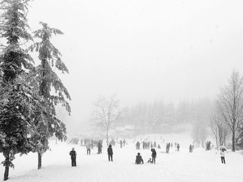 People on snow covered landscape against clear sky