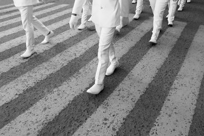 Low section of people in parade walking on zebra crossing