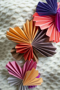 Multi-colored paper hearts arranged on textured knit background