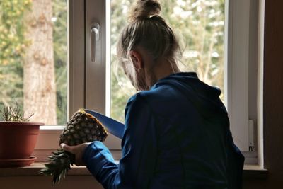 Side view of woman holding window at home