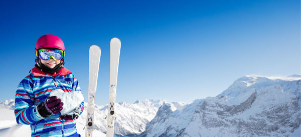 Rear view of woman standing on snowcapped mountain against clear blue sky