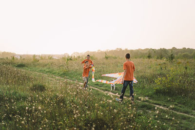 Happy family and children run on meadow with a kite in the summer on the nature.
