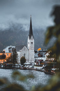 Buildings at waterfront against cloudy sky