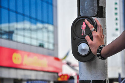 Cropped hand of person touching road signal
