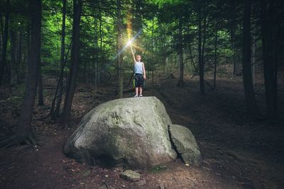 Boy standing on rock in forest