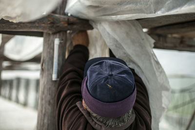 Rear view of man tying fabric on wood