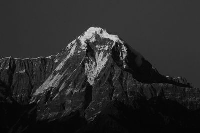 Low angle view of snowcapped mountains against clear sky