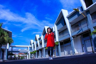 Low angle view of woman walking on footpath against building